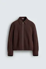 Cazadora boxy fit marrón de corte corto, confeccionada en tejido con mezcla de lana. Presenta cuello camisero, cierre frontal de cremallera metálica, bolsillos de vivo en la cadera y mangas largas.