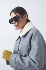 Campera corta de paño color gris con cuello de corderito blanco, cierre frontal con botones y bolsillos laterales.