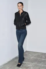 Jeans de tiro medio con corte bootcut y ajuste slim. Presenta diseño de cinco bolsillos, trabillas en la cintura y cierre frontal con cremallera y botón. Incluye detalle de pespuntes marcados a contraste.