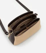Cartera bandolera de tamaño mediano con diseño bicolor que combina paneles de gamuza sintética en color beige con laterales y correa en cuero sintético marrón oscuro. Cuenta con asa larga ajustable y tres compartimentos internos para organización.