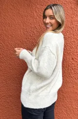Sweater de punto en color crudo melange, con cuello redondo, mangas largas con puños ajustados y diseño de corte holgado.