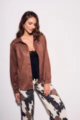 Camisa color marrón de gamuza sintética, de corte recto, con cuello clásico, cierre frontal con botones y mangas largas.