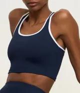 Top deportivo sin copa, color azul marino, con escote en U y espalda tipo nadador. Presenta ribetes contrastantes blancos en el escote y los bordes de las sisas.