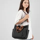 Bolso tipo shopper color marrón de lona, con múltiples bolsillos externos, doble asa de mano y correa ajustable para el hombro.