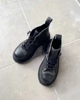 Botas acordonadas de cuero vacuno con efecto desgastado, de caña media y suela track robusta. Presentan costuras a la vista en tono contrastante y tirador en la parte trasera.