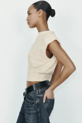 Jersey de punto sin mangas con cuello redondo, diseño de hombreras marcadas y textura acanalada horizontal.