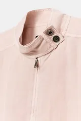 Chaqueta Zara de corte holgado con efecto lavado, cuello subido, cierre frontal con cremallera y botones a presión. Presenta dos bolsillos de plastrón con solapa y botones en el delantero, mangas largas y bajo ajustable con cordones.