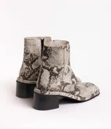 Botín de cuero con estampado de piel de serpiente en tonos blanco y negro, con puntera cuadrada y tacón bloque bajo.