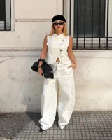 Conjunto de dos piezas color blanco, compuesto por un chaleco sin mangas con cuello mao y cierre frontal cruzado con trabas y botones decorativos, y un pantalón holgado de tiro medio-alto de corte ancho.