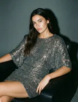 Vestido corto de lentejuelas plateadas, con cintura elastizada, escote en la espalda y forro interno a tono.