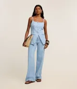 Chaleco largo de jean con escote recto, breteles finos ajustables y cierre frontal con botones. Presenta un corte acinturado con pences, bolsillos delanteros decorativos y ruedo en punta.