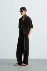 Polo de manga corta confeccionado en tejido de punto calado con estructura abierta. Presenta un diseño de corte relajado, cuello solapa con abertura frontal en pico y terminaciones acanaladas en puños y bajo.