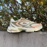 Championes Lacoste modelo Storm 96 2K, con diseño deportivo de estilo retro. Presenta una combinación de colores en tonos crema, beige, rosa suave y verde oliva. Incluye el logo del cocodrilo característico en el lateral y una suela robusta con relieve.