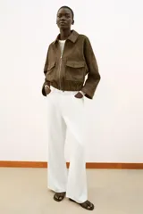 Cazadora de efecto ante con cuello solapa, cierre frontal con cremallera y mangas por debajo del codo. Presenta bolsillos delanteros de plastrón con solapa y bajo elástico.