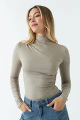 Body color visón con cuello tipo polera y mangas largas. Tiene frunces en los costados.