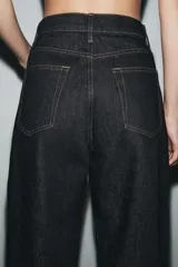 Jeans de tiro medio con corte tapered, confeccionados en denim de color negro con costuras en contraste. Presentan diseño de cinco bolsillos, trabillas en la cintura y cierre frontal con cremallera y botón.