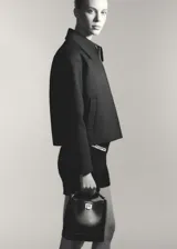 Chaqueta negra de diseño oversize con cuello camisero y cierre frontal de cremallera. Cuenta con forro interior y bolsillos laterales.