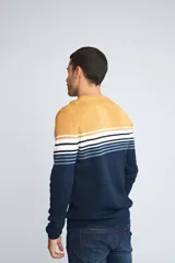 Sweater de punto con diseño de bloques de color, presentando una sección superior roja, una franja central con rayas horizontales en blanco, negro y gris, y una sección inferior negra. Posee cuello redondo, mangas largas y logo bordado en el pecho.