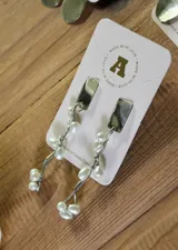 Aros colgantes plateados con base rectangular y perlas colgantes.