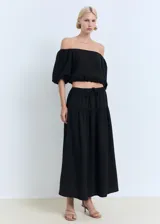 Falda larga evasé de tiro bajo y color negro, confeccionada en tejido 100% algodón, con cintura elástica y cordón ajustable.