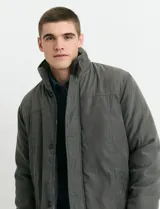 Campera de estilo Harrington en color verde oscuro, con cuello alto, cierre frontal y solapa con botones.