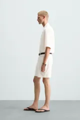 Bermuda de algodón color blanco, de corte relajado, con cintura elástica, bolsillos frontales y bolsillos traseros de plastrón. Cierre frontal con cremallera y botón.