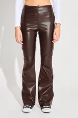 Pantalon de ecocuero color marron oscuro, de tiro alto y corte semi oxford. Presenta un cierre metalico lateral y un recorte horizontal sobre la rodilla.