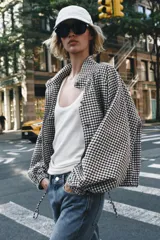 Chaqueta de manga larga con estampado de cuadros vichy en tonos marrón y blanco, cuello camisero, cierre frontal con botones y bajo ajustable con cordón.
