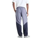 Pantalón New Balance Sport Legacy, diseño bicolor en tonos gris y azul marino, con cintura elástica ajustable mediante cordón y logo bordado en blanco.