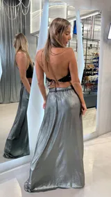 Pollera larga de satén plateado con acabado metalizado, corte evasé, cintura alta y tajo lateral profundo.