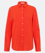 Camisa de manga larga color verde lima, con cuello camisero y botonadura frontal. Presenta un dobladillo trasero más largo que el delantero.