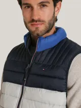 Chaleco acolchado Tommy Hilfiger con diseño triblock en azul marino, gris y azul. Cuenta con cuello alto, cierre de cremallera frontal, dos bolsillos laterales con cremallera y logo bordado en el pecho.