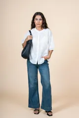 Blusa de algodón color blanco con bordado sutil en relieve, cuello redondo, cierre frontal con botones y mangas tres cuartos con terminación elástica.