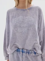 Buzo de felpa con efecto lavado acid wash, de corte oversized y manga larga. Presenta estampa frontal con texto y estrellas.