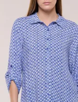 Camisa azul con estampa geométrica, de corte clásico y calce relajado, con cuello camisero tradicional, cierre frontal de botones y mangas largas con presillas para arremangar.