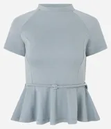 Blusa de punto Roma color celeste, con cuello alto, mangas cortas y diseño peplum. Presenta recortes estructurales y un cinturón integrado con hebilla metálica en la cintura, finalizando en un ruedo con volados.