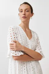 Vestido largo negro con tejido calado tipo broderie inglés, escote en V, mangas cortas con volado y diseño de capas con volados en el ruedo.