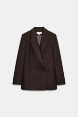 Blazer de corte sastre con cuello solapa, manga larga y hombreras marcadas. Presenta un diseño cruzado con cierre frontal de botones, bolsillos delanteros de vivo y abertura posterior en el bajo.