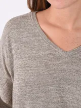 Buzo de tejido de punto fino color gris melange, con escote en V, mangas largas con detalle de volado en los hombros y corte holgado.