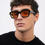 Lentes de sol con armazón cuadrado de color negro y bordes gruesos, inspirados en la moda de los años 70. Poseen cristales de color naranja con protección UV400.