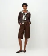 Suéter de punto color marrón chocolate, con cuello redondo y mangas largas con puños acanalados. Presenta un diseño básico y versátil de corte recto.