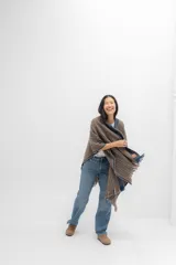 Ruana marrón con rayas horizontales azules y blancas, y flecos en los bordes.