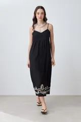 Maxi vestido negro de breteles finos con escote recto y bordado floral en el ruedo.