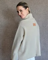 Sweater color crudo de cuello alto con mangas largas y corte holgado.