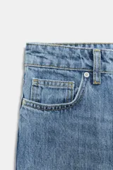 Jeans capri de tiro medio con diseño de cinco bolsillos, cintura con trabillas y cierre frontal con cremallera y botón. Presenta un acabado con efecto lavado.