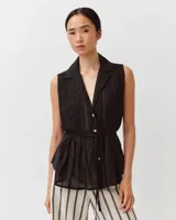 Camisa sin mangas color negro de algodón, con cuello camisero, cierre frontal de botones y lazo ajustable en la cintura.
