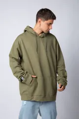 Buzo canguro oversize de tela friza, color negro, con capucha, cordones ajustables con logo y bolsillo frontal tipo canguro.