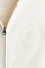 Campera con capucha de algodón pesado, color blanco hueso, de corte holgado y hombros caídos. Posee cierre frontal bidireccional, bolsillos canguro delanteros y puños y bajo acanalados.