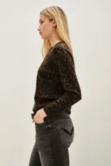 Sweater de punto con estampado animal print en tonos verde oliva y negro, de cuello redondo y manga larga con puños acanalados.