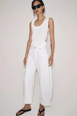 Jeans de tiro medio de corte balloon leg, color blanco, con trabillas en la cintura, diseño de cinco bolsillos, bajo con vuelta y cierre frontal con cremallera y botón.
